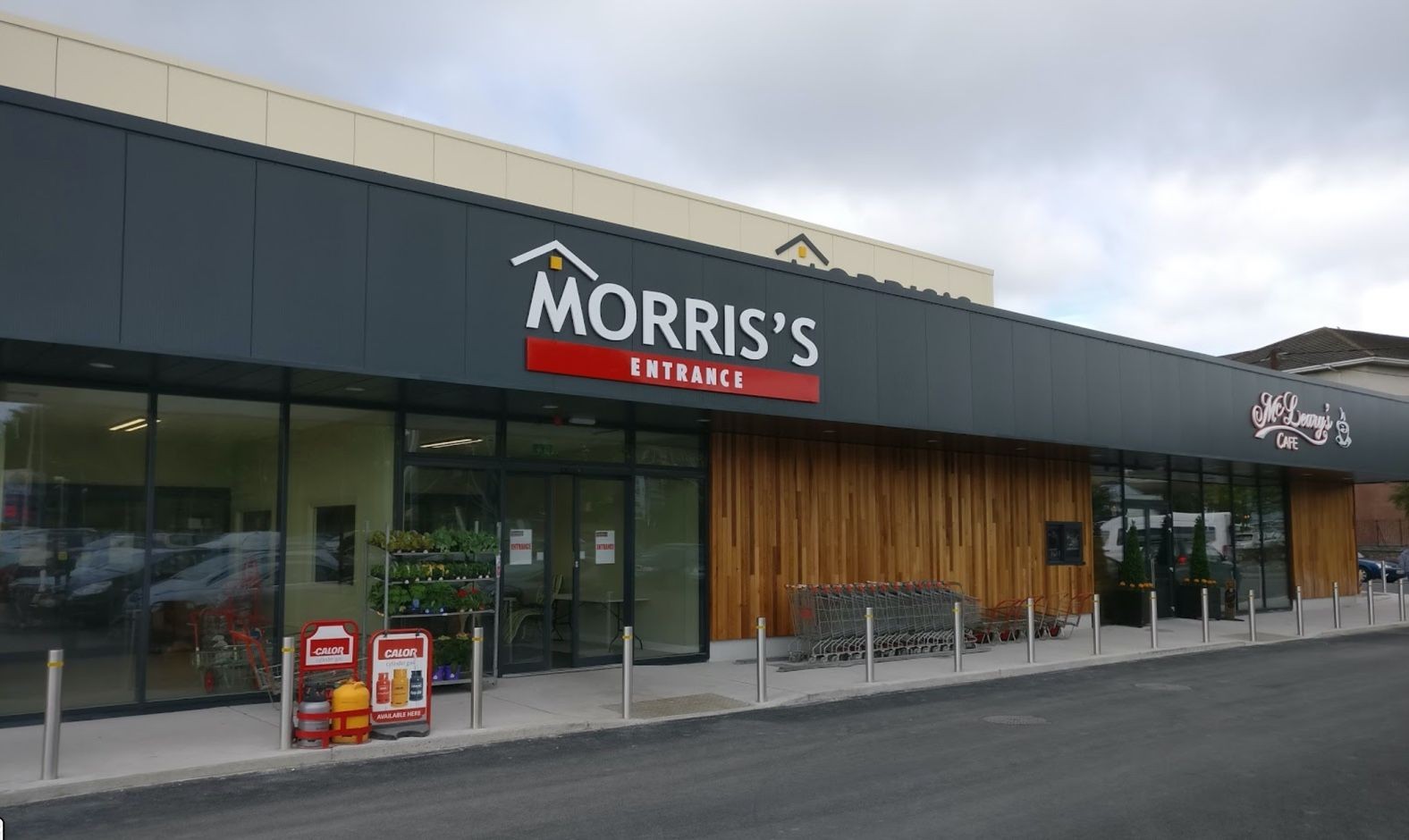 Exterior view of a store entrance with shopping carts and signs, featuring dark panels and wooden accents.