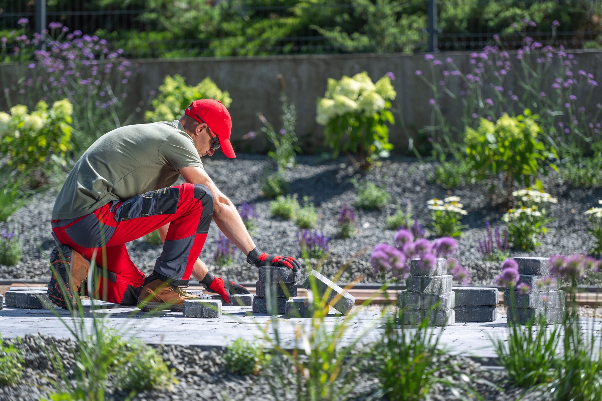Gardener Laying Stones for a Pathway in a Blooming Flower Garden on a Sunny Day