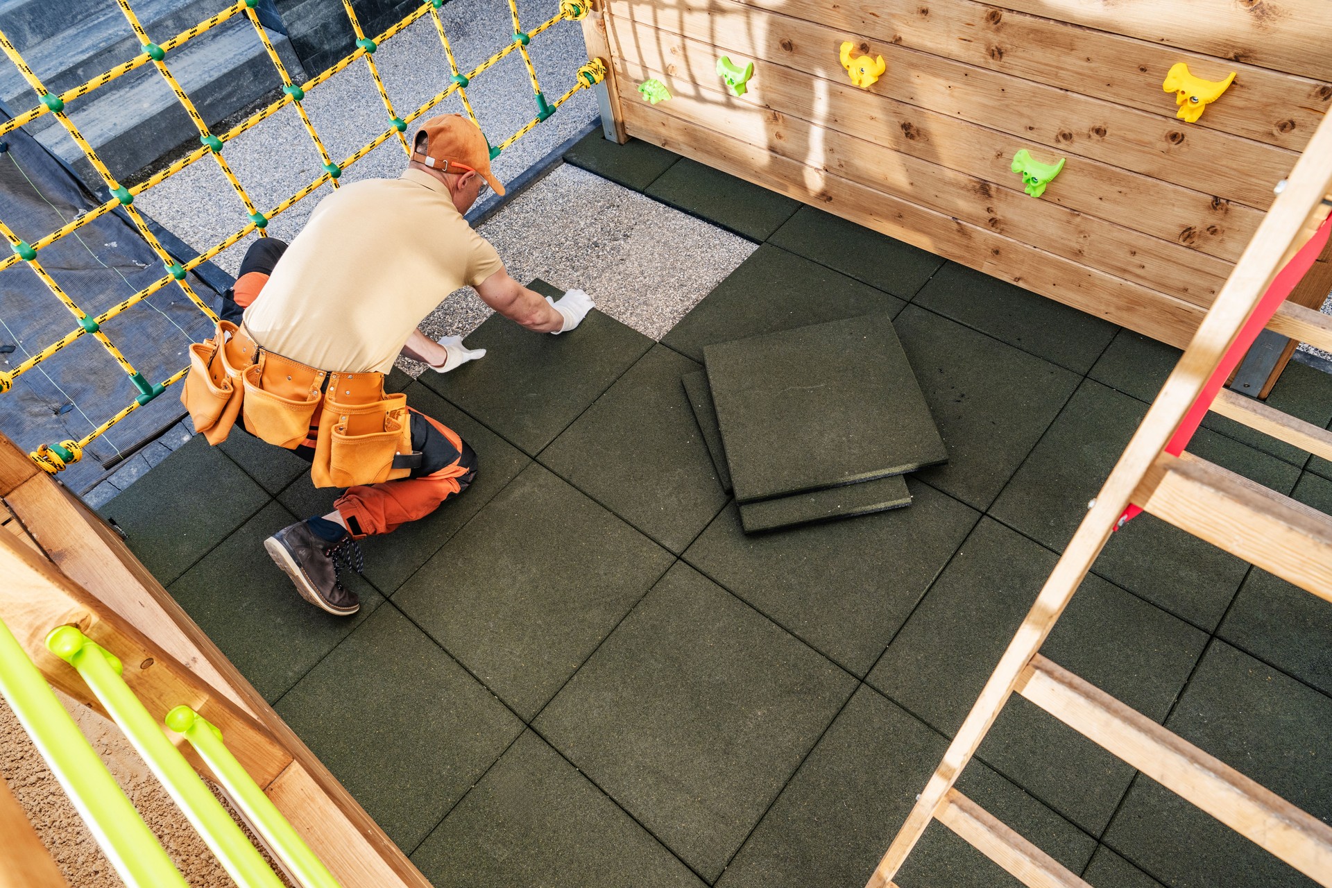 Worker Installing Safety Tiles in a Playground Area During Daylight Hours